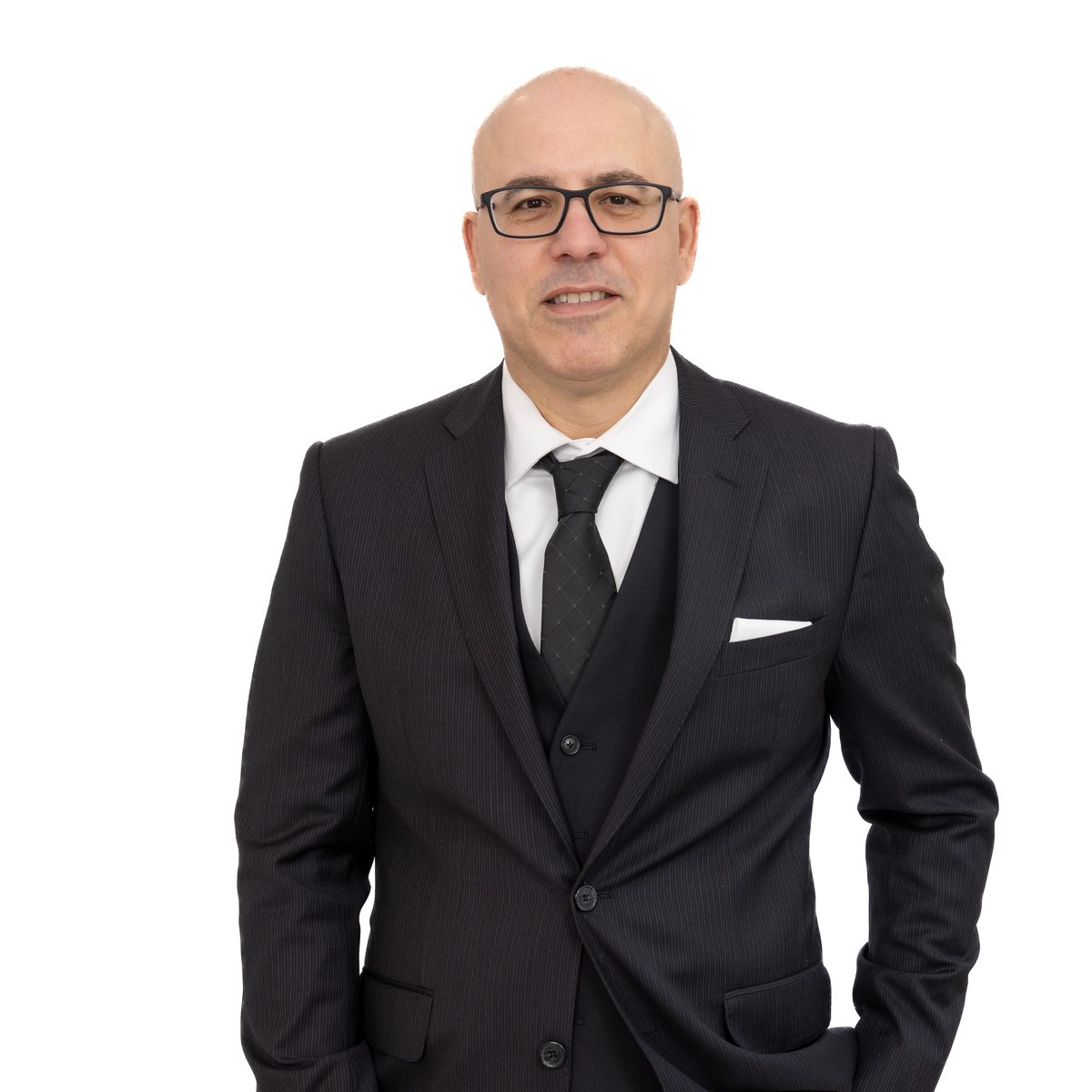 Corporate headshot of a smiling man with glasses in a dark three-piece suit and tie against a white background.