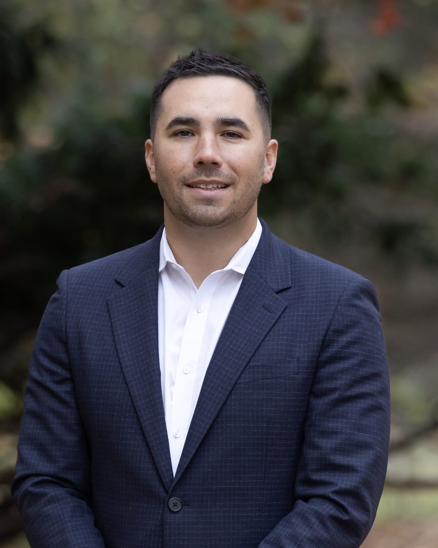 Portrait of a professional in a navy blazer and open collar photographed outdoors in soft autumn light.