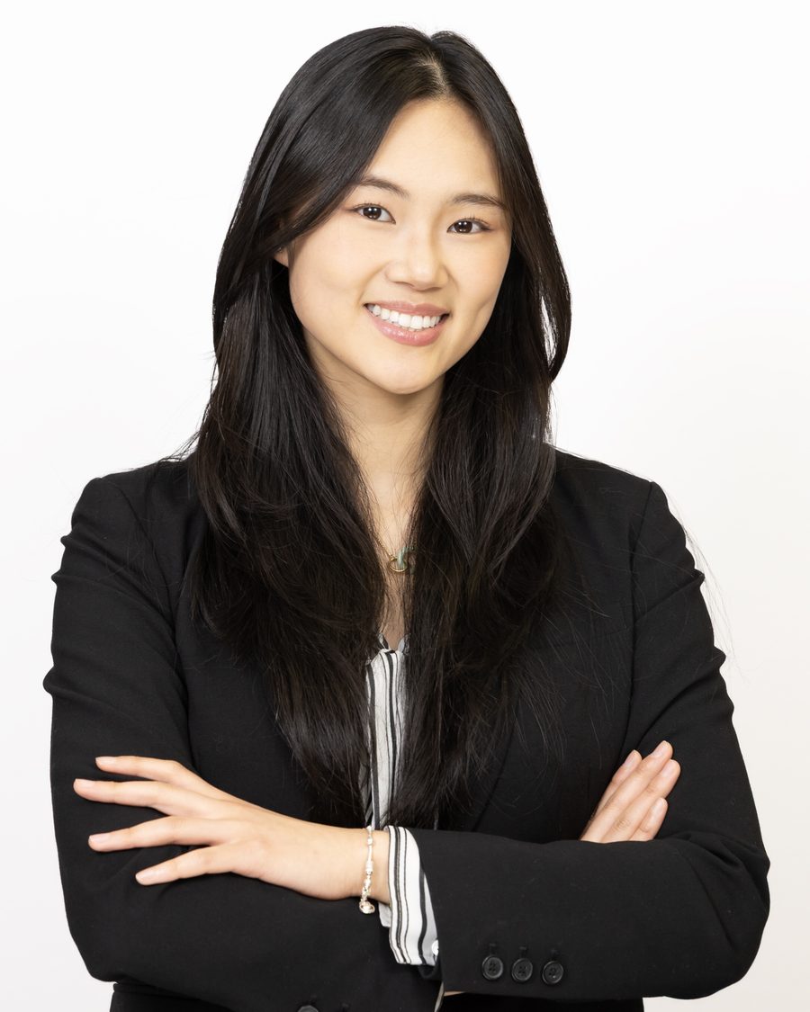 Corporate headshot of a professional in a black blazer and striped shirt on a white studio background.